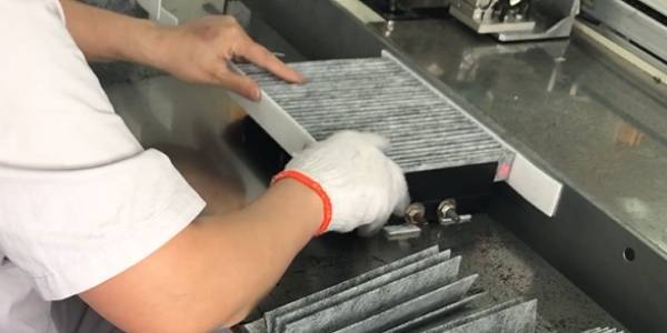 A machine is bonding and trimming the cabin filter edge.
